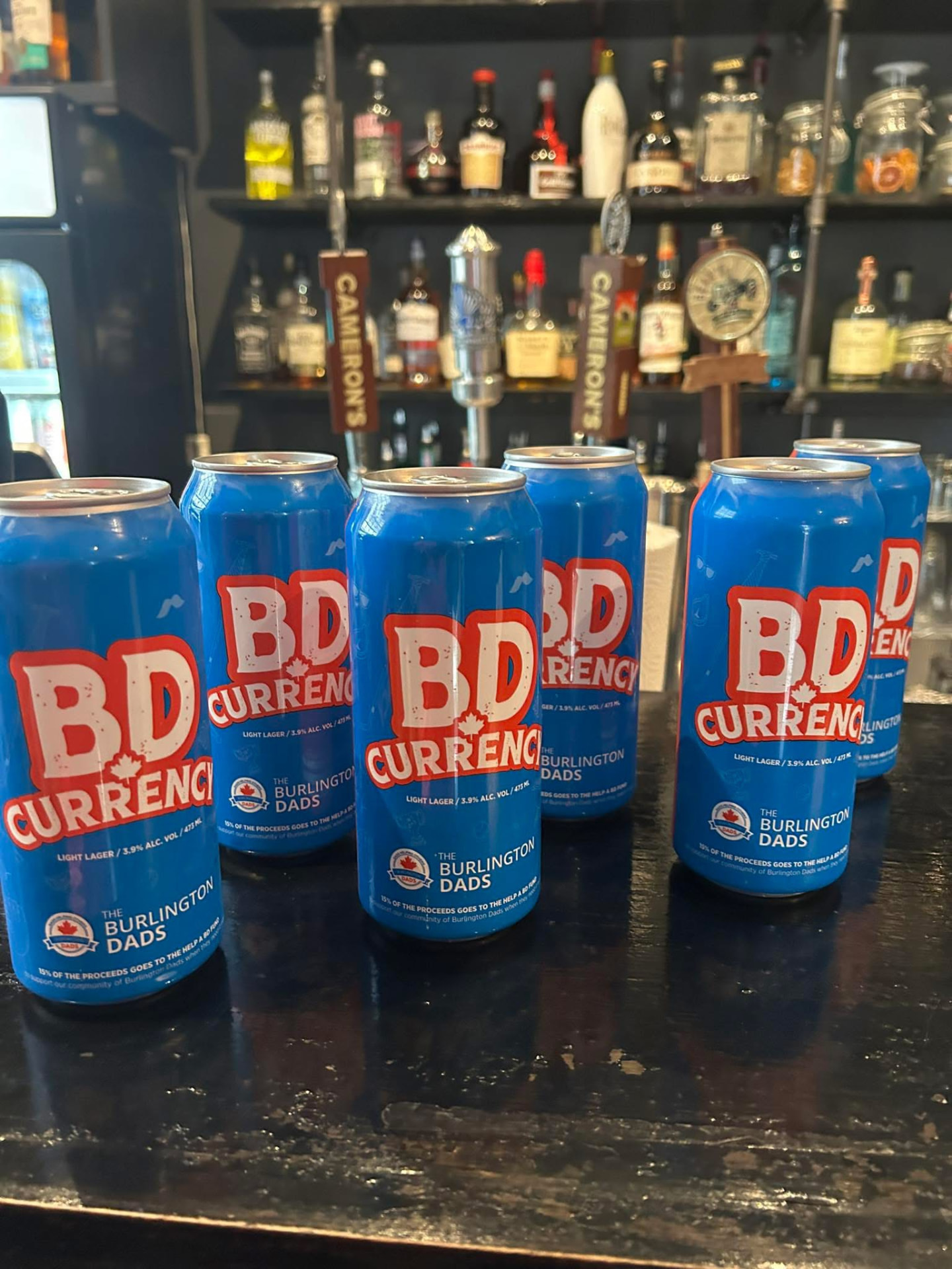 Cans of BD Currency light lager lined up on a bar top